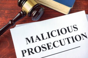 Malicious prosecution and gavel on a table.